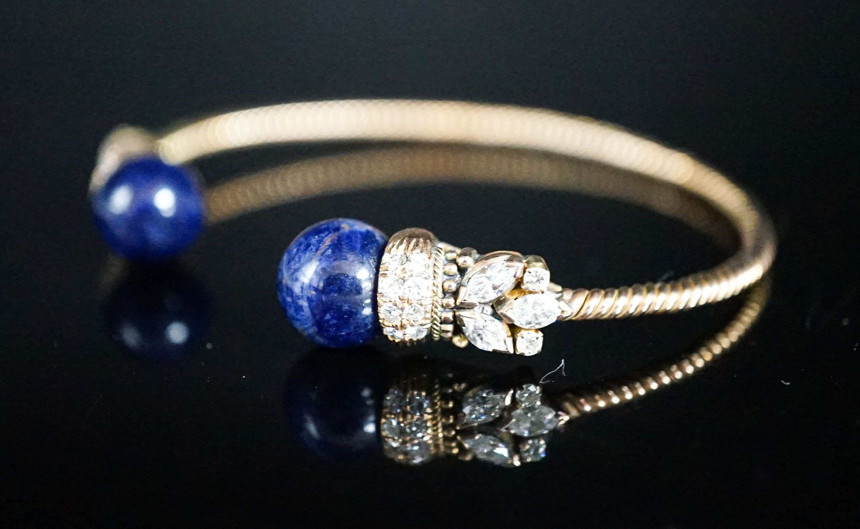 A modern yellow metal twist, two stone sodalite? and diamond set open bangle, gross weight 14 grams.